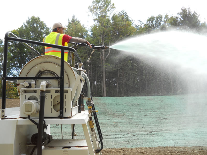 Technician spraying hydroseed mixture on prepared soil